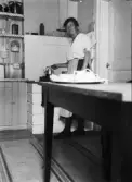 Inez Hällbom står vid spisen och kokar kaffe, Uppsala, Uppland