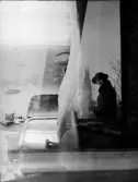 Dubbelexponerad - Bostadsinteriör/ Kvinna sitter vid Gunillaklockan , Uppsala, Uppland
