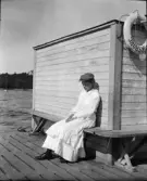 Flicka sitter på en bänk på bryggan, Norsborg, Södermanland