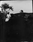 Kvinna sitter på ett berg, Uppland