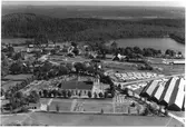 Flygbild över Torup med kyrka, kyrkogård och en träindustri i förgrunden. På andra sidan järnvägen ses en del bebyggelse vid Sjögårdsjön, där skogen tar vid.