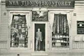 Reklamkort i svartvitt med bild på W. Wahlunds Nya tidningskontoret, Bok- & Papperhandel. Text på baksidan.