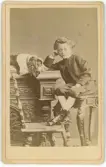 Porträtt på prins Eugen sittande på ett bord, och på bilden syns även en hund.
