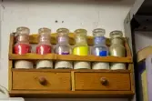 Glasburkar med pigment på trähylla 