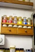 Glasburkar med pigment på trähylla 