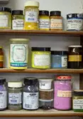 Glasburkar med pigment på trähylla 
