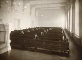 Hvitfeldtsskolan (Hvitfeldtska) uppfördes åren 1915-1919 och arkitekt var Ernst Torulf.
Hvitfeldtsskolans aula. Provskrivning i högre folkskolan.
Rektorsgatan 2