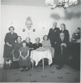 Nio personer sitter/står vid ett bord i 