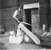 Leksand. Yttermo. Nygårds Anders vid skavbommen*

* En skavbom är ett traditionellt hantverksredskap som används inom garvning och skinnberedning för att skrapa djurhudar. Den består av en rundad, lätt konvex stock – ofta klädd med zink- eller bleckplåt för att göra ytan hal och rostfri – och används tillsammans med en skavkniv för att ta bort kött, fett och hår från skinnet.

Källa: Wikipedia
