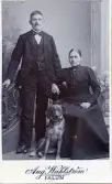 Porträtt av kvinna och man med en hund bredvid sig.