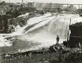 Byggandet av Älvkarleby kraftverk med en man som står och fiskar vid älven, omkring år 1906 (enligt text i album).