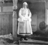 Mora. Morakeling i kasung, nidåkasung och stjim. (Morakvinna i vit fårskinnspäls, kjol och förkläde)

