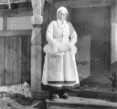 Mora. Morakeling i kasung, nidåkasung och stjim. (Morakvinna i vit fårskinnspäls, kjol och förkläde)

