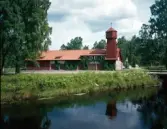 Gamla brandstationen i Hyltebruk omgiven av träd vid kanalen.