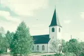 Exteriörbild. Hyltebruks kyrka omgiven av träd och buskar.