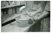 Tillverkningsprocessen hos Bo Fajans, omkring 1946-1950. Arbetsstation för glasering av godset genom doppning.