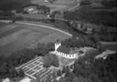 Flygbild över Färgaryds kyrka och kyrkogård vid ån Nissan med omgivande odlingslandskap. Bilden är tagen från sydöst. Kyrkan uppfördes 1845-1846 i nyklassicistisk stil under ledning och efter ritningar av byggmästare Petter Pettersson.