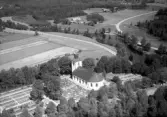 Flygbild över Färgaryds kyrka och kyrkogård vid ån Nissan med omgivande odlingslandskap och skog. Östlig vy.