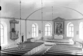 Interiörbild från Färgaryds kyrka. Vy från läktaren över den slutna bänkinredningen mot det rundade koret. Predikstolen tillverkad av J A Andersson installerades 1871 och nås via en uppgång i sakristian. Altartavlan 