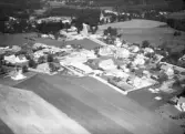 Flygbild över Hishult med villaområden och annan bebyggelse sydöst om kyrkan i fokus. Odlingslandskapet når inpå samhället.