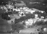 Flygbild över Hishult med bebyggelsen utmed Markarydsvägen. I bildens centrum ses skolan och i övre delen skymtar kyrkan. Samhället kantas av skog och odlingslandskap.