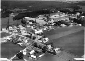 Flygbild över Hishult med bostadshus, bondgårdar, skola, odlingslandskap och skog.