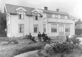 Tvåvåningsbyggnad i trä med bred balkgong över entrén. Framför huset sitter och står medlemmarna i fattigvårdsstyrelsen i Släp. Från vänster: nämndeman Herman Ekström, Alfred Larsson, Patrik Johansson, Emil Nilsson, okänd, Elin Lagerkvist, fru Classon. Ytterligare en person står i fönstret på övervåningen. I förgrunden en rabatt med rosor.