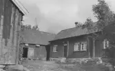 Kringbyggd gård med stensatt gårdsyta i Kyrkobyn, Släp socken. Bostadshuset är timrat.