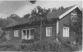 Långsträckt bostadshus Stocken, Släp socken. Entrépartiet är indraget med räcke och pelare i fasdalivet.