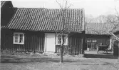 Torp Spårhaga 1, Släp. Litet bostadshus, sammabyggt med en större byggnad och uthus kring en stensatt gårdsyta till höger i bild. En kärra står på gården.