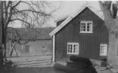 Gården Nötegång, Släp socken. Bostadshuset sett från gaveln och en ekonomibyggnad. På och vid stengärdsgården ligger stockar. Elledningar på gaveln.