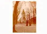 Varbergs kyrka fotograferad från Brunnsparken, där två kvinnor promenerar.