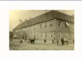 Varbergs Hotell i hörnet av Borgmästaregatan-Drottninggatan. I  januari 1898 brann hotellet ned. Utanför hotellet står några pojkar, en man med dragkärra och en i hästdragen vagn.