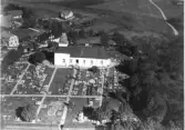 Flygbild över Slättåkra kyrka med kyrkogård och de närmaste gårdarna.