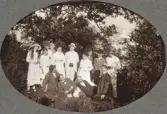 Ett sällskap med män, kvinnor och barn poserar för fotografen i en skogsglänta, en varm sommardag.
Trol. Amos Svensson med familj och vänner.