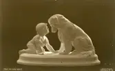 Brevkort med motiv, pojke och hund staty. Text på framsidan 