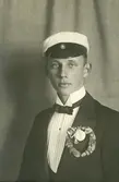 En ung man i studentmössa och smoking.
Bröstbild, halvprofil.
Trol. Seved Svensson, student v. Växjö läroverk 1913.
