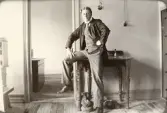 En ung man poserar på ett kontor, halvt sittande på ett skrivbord.
Trol. Seved Svensson på postkontoret i Skurup, dit han flyttade för att arbeta i december 1917.