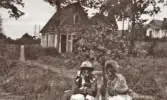 Två unga kvinnor vid ett litet äppelträd (?).