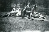 Siesta i sol. Beredskap i Åhus 1944 (enligt text i album). Text baksida kort: Från vänster: K o Gustavsson, Sjögren, Gisslén, Aneborn (?) ,Olsson, Berglin, Wiberg. Åhus juli 1944.