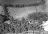 Flygbild över Mäshult i Skällinge. I nedre delen ses jaktslottet från 1800-talets mitt med annex och ekonomibyggnader. Bakom byggnaderna står höhässjor på åkrarna ner mot sjön Mäsen. Landstinget bedrev skyddshem för försummade barn här 1880 till 1937, då Mäshult togs över av staten och blev skolhem för pojkar. Efter olika funktioner såsom fängelse och flyktingsluss är det idag vandrarhem och kursgård.
