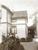 Ett träpanelat bostadshus i en trädgård. Möjl. Kalmar.
