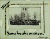 En konfirmationsklass har samlats med prästen framför kyrkan i Linneryd.
Inglasat foto med ljust turkos passepartout med dekorationsbård i svart, vitt och guld på tre sidor och text:
