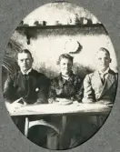 En medelålders kvinna och två män sitter i en soffa och betraktar fotografen,
