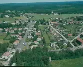 Flygbild över Knäred med småskalig bebyggelse utmed vägarna och Knäreds kyrka i bakgrunden, där skogen breder ut sig.
