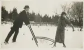 En man och en kvinna med en sparkstötting i en snöig hage.