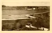 Oskrivet brevkort med motiv från Kungsgården, Ovansjö. På bilden syns Kungsgårdens herrgård i bakgrunden medan en del av kyrkogården skymtas i förgrunden. Motiv och tryckning från L. Westin, Storvik.