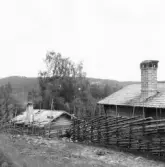 Gagnef. Stugor vid fägatan i Gråbuan. Nolbäcksbuan i berget i bakgrunden. 1920.