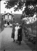Tre kvinnor framför hus